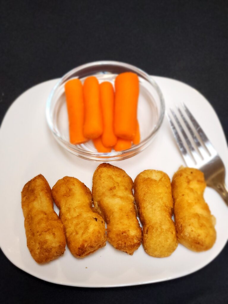 Tyson Batter Dipped Chicken Breast Tenders and carrots on a plate with a fork.